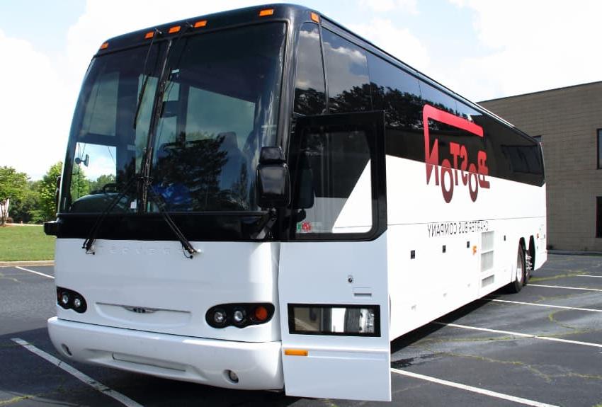 A br和ed Boston Charter Bus Company charter bus parks in an empty parking lot, door open wide for passengers to board